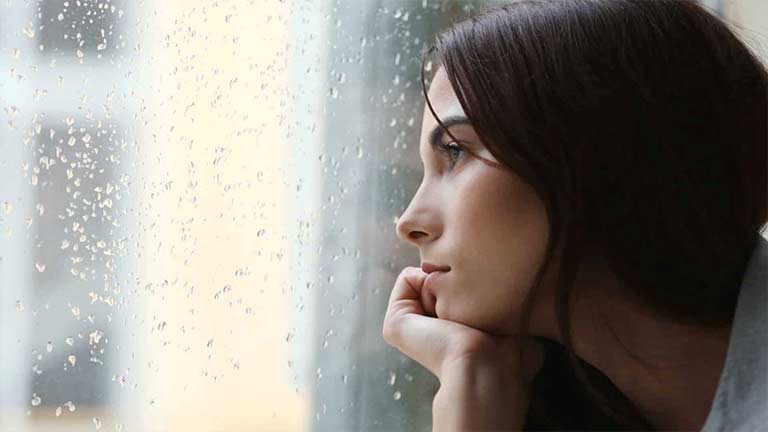 A woman gazing out of a rainy window