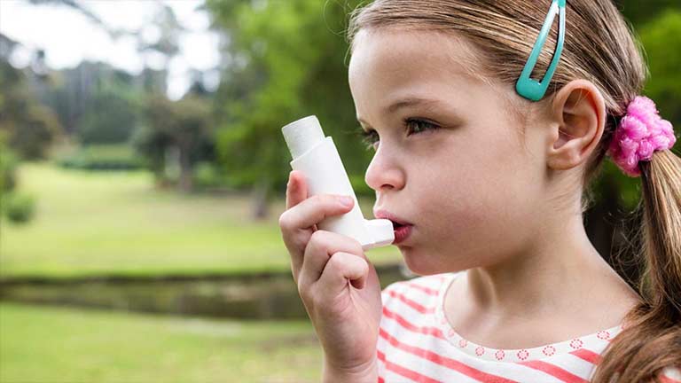 Young girl managing her asthma symptoms with an inhaler