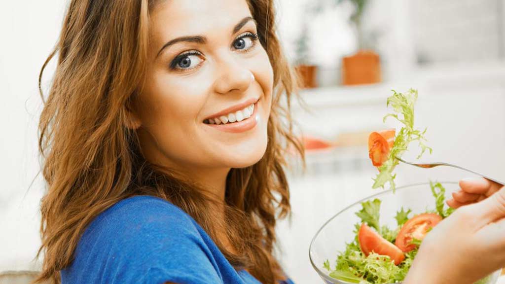 Happy. healthy young woman eating a salad