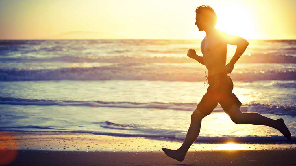 Man running on beach at sunset