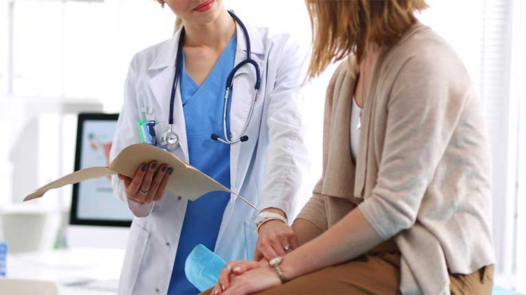 Female doctor holding a medical chart talking to a female patient