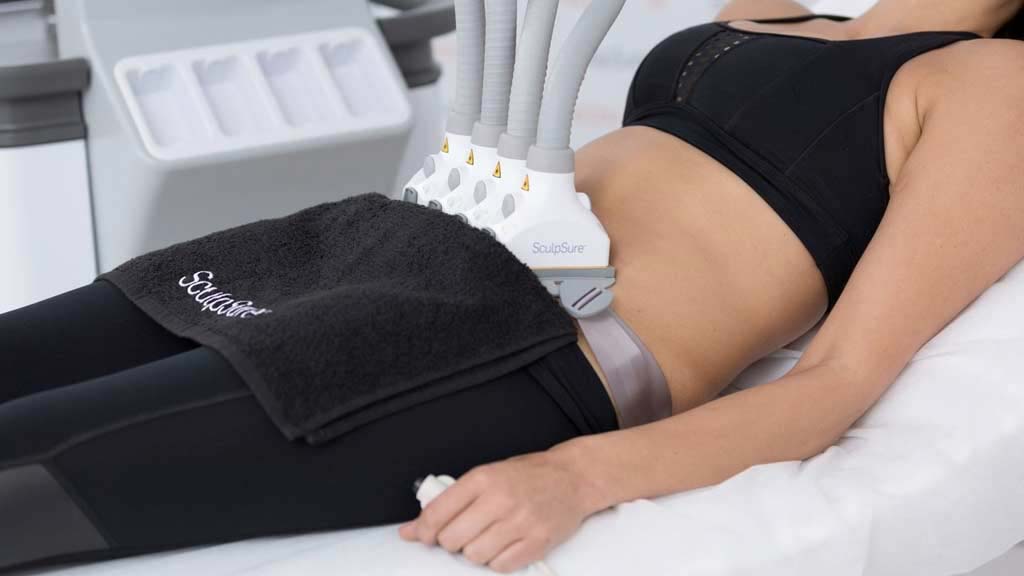Woman laying on her back with the SculpSure machine during body contouring procedure