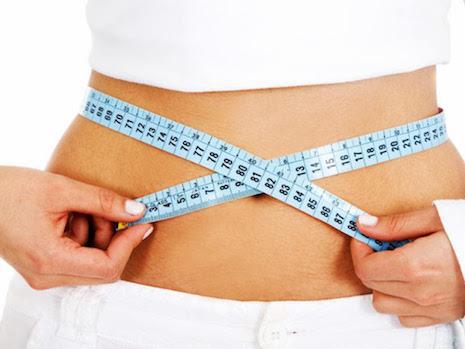 Woman measuring her waist with a tape measure