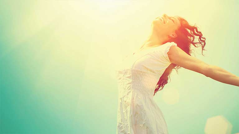 Healthy woman with arms outstretched looking to the sky